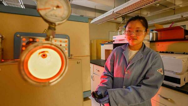 A female student operates an incinerator used for Per- and polyfluoroalkyl substances (PFAS) research in the Kyle Doudrick lab. The incinerator glows red with heat.